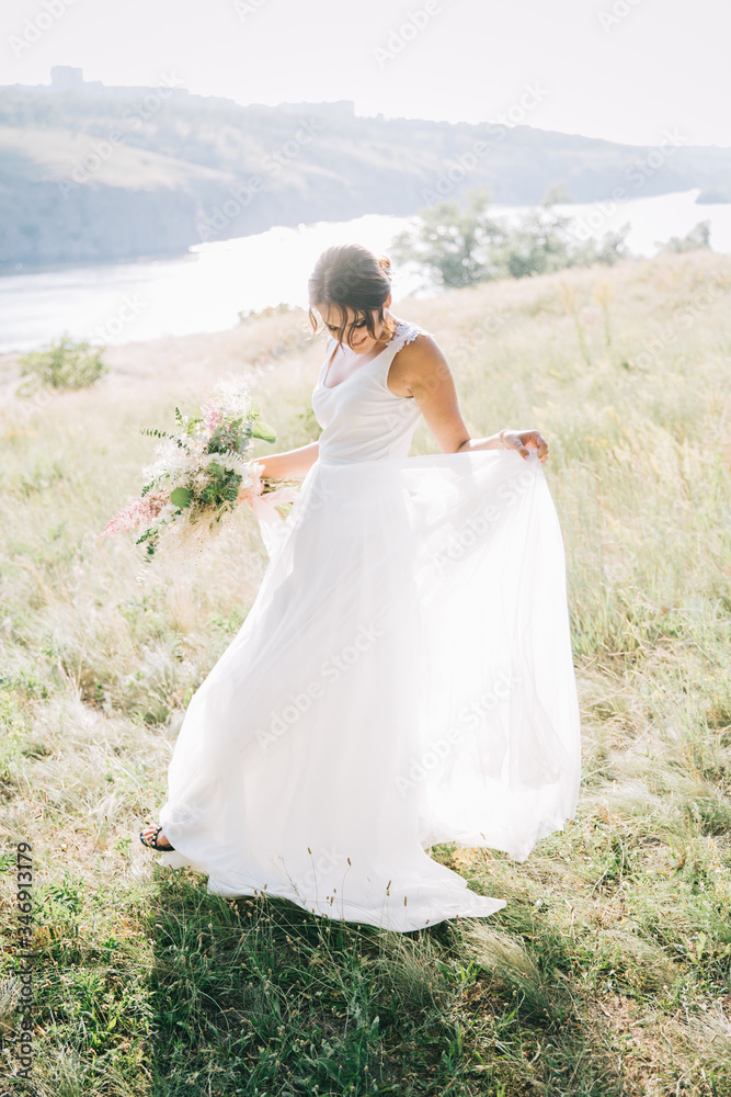 Bride in a luxurious white wedding dress in nature at sunset	