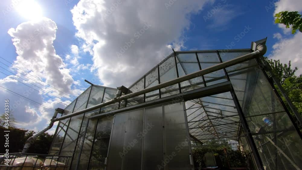 Timelapse of clouds racing past a small industrial greenhouse hothouse glasshouse Timelapse of clouds racing past a small industrial greenhouse hothouse glasshouse
