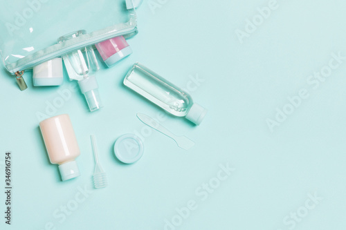 Top view of means for face care: bottles and jars of tonic, micellar cleansing water, cream, cotton pads on blue background. Bodycare concept with empty cpace for your ideas