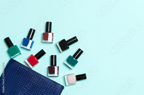 Fototapeta Naklejka Na Ścianę i Meble -  Top view of the set of nail polishes and bright gel varnishes fallen out of cosmetics bag with copy space on blue background. Trendy nail concept