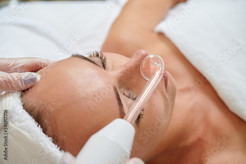Tableau sur toile Female receiving galvanic facial treatment in spa cosmetologist wearing gloves professional services