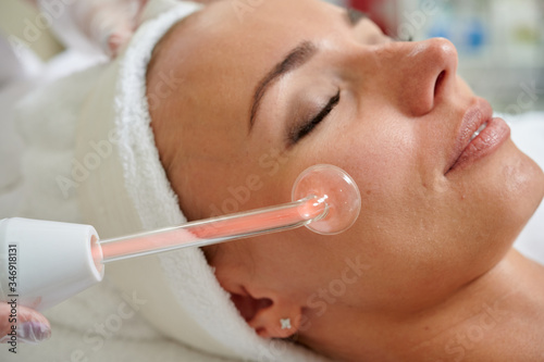 Female receiving galvanic treatment in spa cosmetologist professional services.