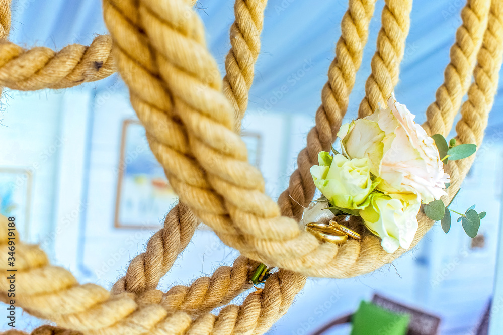 Golden wedding rings on sea rope
