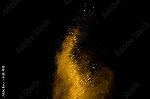 Yellow powder explosion on black background. Colored cloud. Colorful dust explode. Paint Holi.