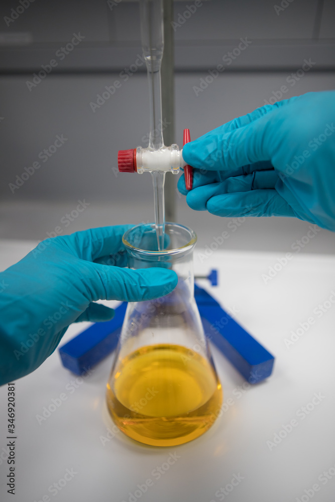 scientist working in laboratory performing a titration using an orange indicator scientist working in laboratory performing a titration using an orange indicator