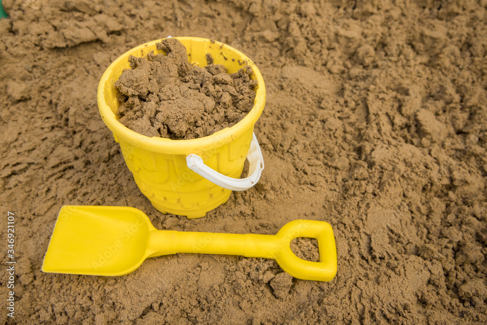Yellow bucket and spade to make sandcastles out of golden sand Yellow bucket and spade to make sandcastles out of golden sand