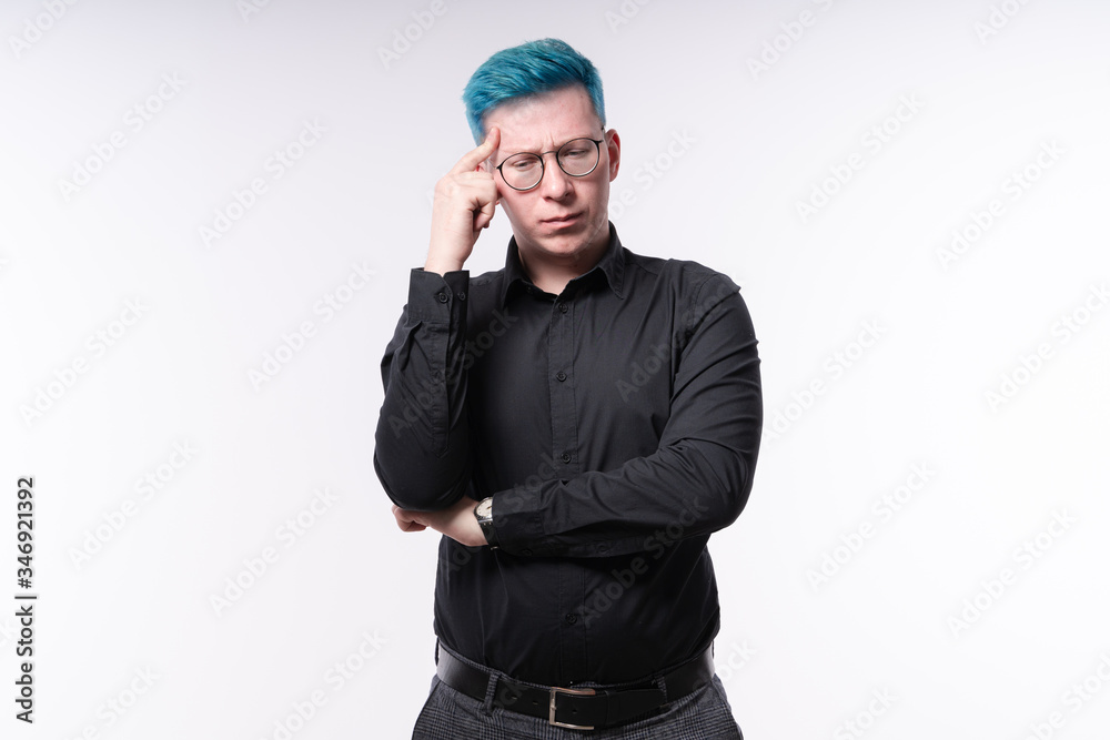 Young blue haired man touching his temple with fingers, expressing serious decision making, studio shooting on light background Young blue haired man touching his temple with fingers, expressing serious decision making, studio shooting on light background
