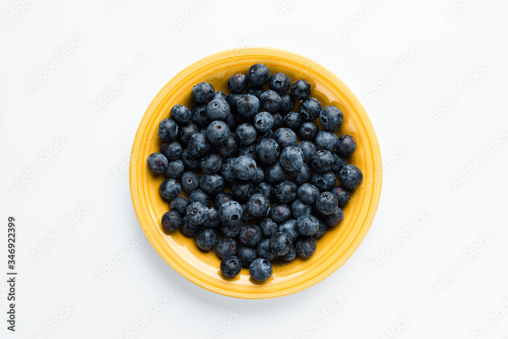 Blue berries in a yellow plate, top view Blue berries in a yellow plate, top view