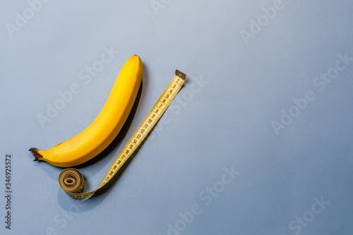 Tape measure and banana on blue background