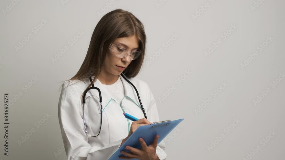 Women doctor of Caucasian appearance writes on paper a 4. Medicine. Health Women doctor of Caucasian appearance writes on paper a 4. Medicine. Health
