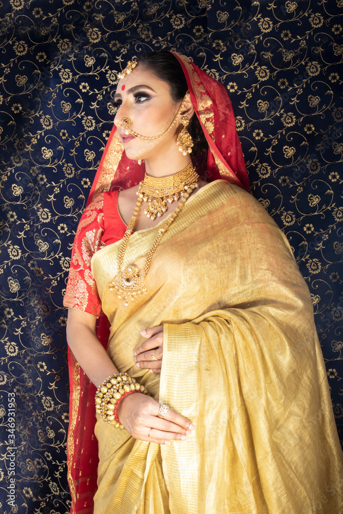 Indian Bridal wear in a golden and red saree and royal jewellry