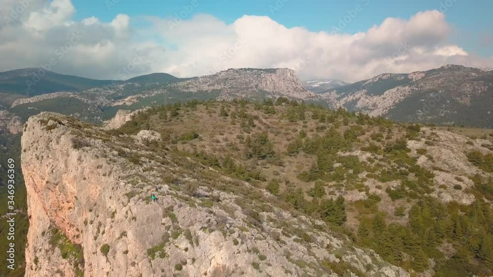 Backwards aerial reveal shot of a girl and a dog sitting at the edge of a cliff. Shot in 4K quality Backwards aerial reveal shot of a girl and a dog sitting at the edge of a cliff. Shot in 4K quality