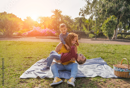 Fototapeta Naklejka Na Ścianę i Meble -  Young mother has fun in the park with her twin sons - Young family having a playful time together at a picnic - Family, mother and childs love concept