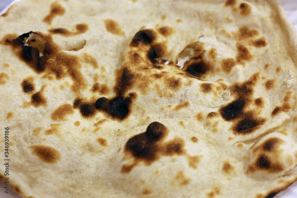Closeup of a naan bread - buttery, white bread often eating with dips. Indian style street food from a food court in a mall located in Dubai. Delicious yet not too healthy food. Color closeup image.