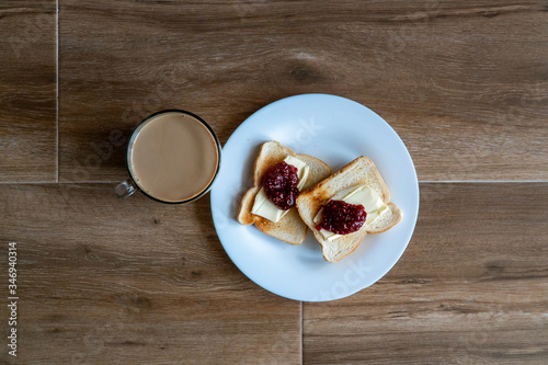 Obraz na płótnie Cup of coffe with milk and two slices of toasted sandwich Bread with Butter and Raspberry Jam a white plate. Healthy breakfast with coffee. Top view. Free space for text. w salonie