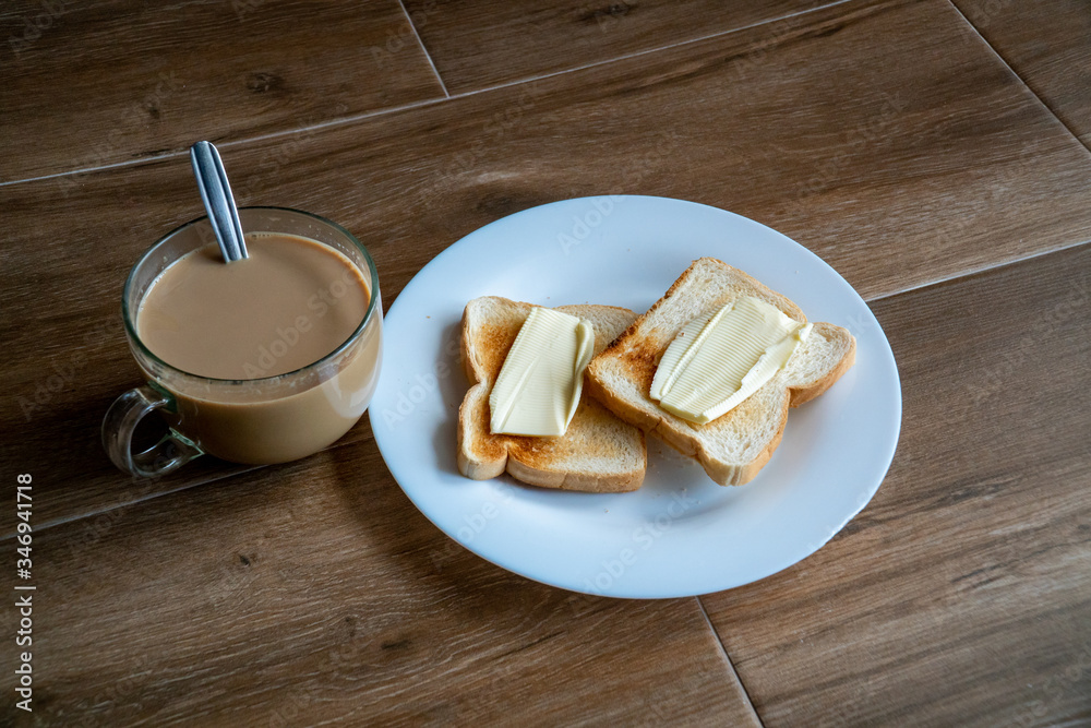 Cup of coffe with milk and two slices of toasted sandwich buttered bread on a white plate. Healthy breakfast with coffee. Side view. Free space for text.