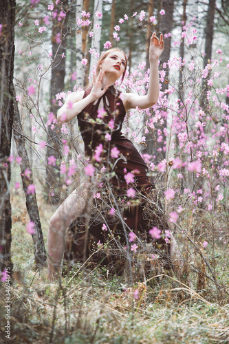 A girl dressed in Japanese style in a flowering forest among pink flowers