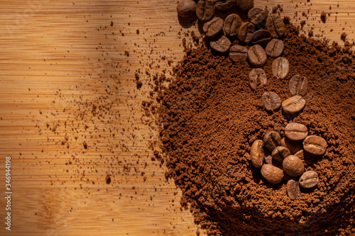 Top view of coffee beans and ground coffee on wooden background, roasted coffee volcano like anthill photo