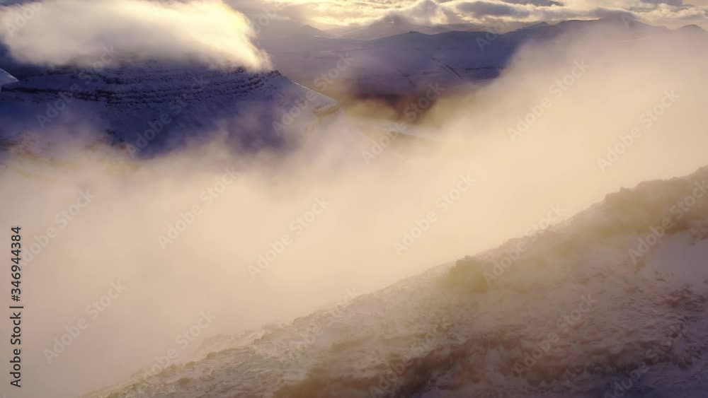 Aerial, drone shot of low clouds on a rocky mountain ridge, foggy sunrise, in the fjords of Faroe islands, Denmark Aerial, drone shot of low clouds on a rocky mountain ridge, foggy sunrise, in the fjords of Faroe islands, Denmark