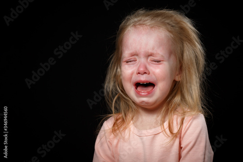 Canvas Print A little girl is crying hysterically in a dark room