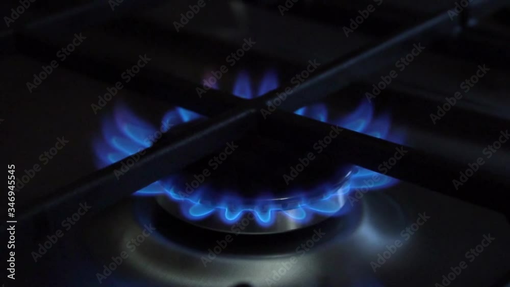 The kitchen burner turns on. The upper burner lights up, turning into a blue flame. Natural gas inflammation, close up.