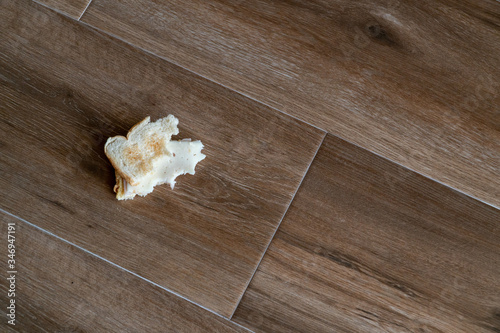 Bread tossed to the floor. Half Eaten Sandwich thrown on the floor. Discarded Sandwich. Thrown into the trash food. Concept.