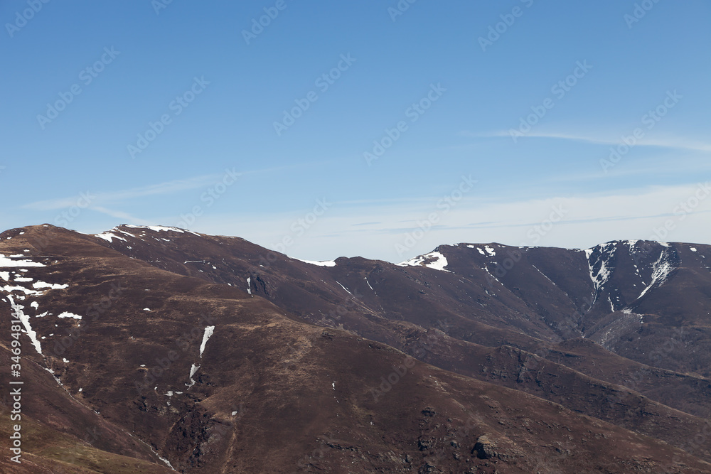 Distant mountains covered by snow and dark, burnt trees and ground, recovering from a fire last summer