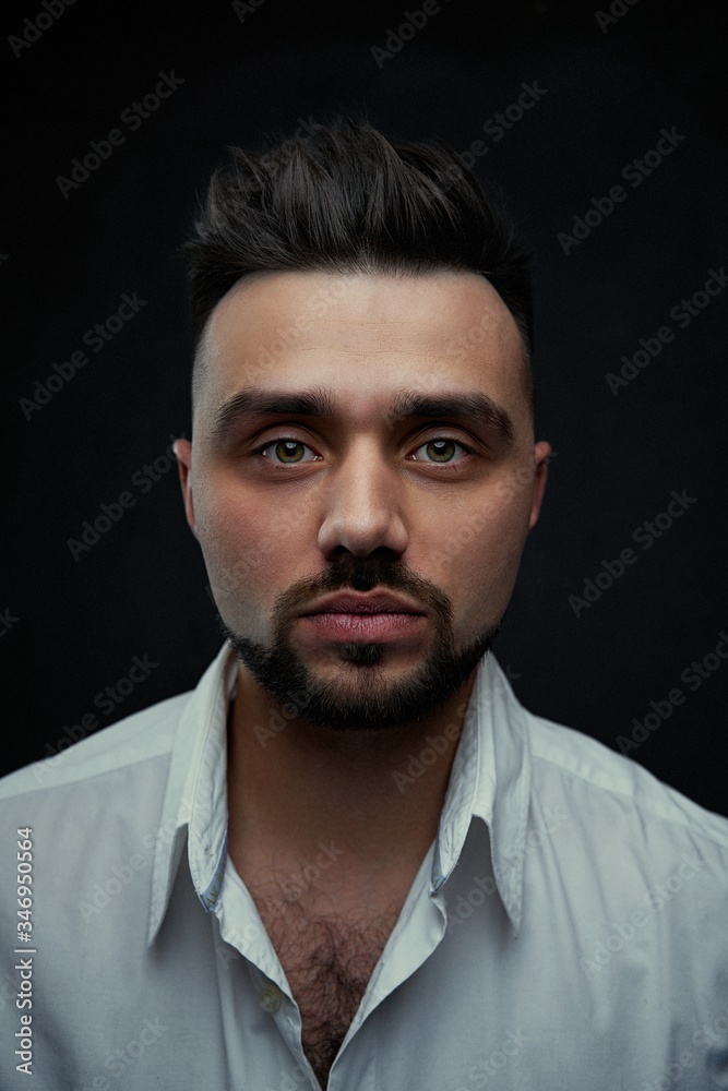 Portrait of handsome young man against studio background. Perfect hairstyle, modern stylish haircut. Attractive guy with fashion hairstyle. Confident man with short beard. Barbershop concept.