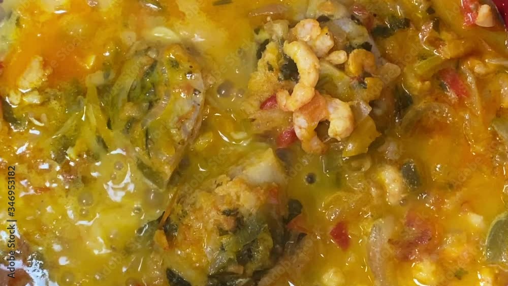 Cooking a moqueca dish. Brazilian traditional food made with fish and shrimp, coconut milk and azeite de dende. Cooking a moqueca dish. Brazilian traditional food made with fish and shrimp, coconut milk and azeite de dende.