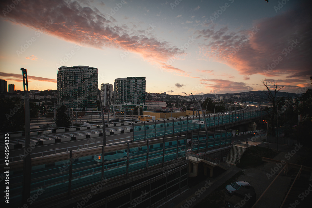 Beautiful sunset in the city of Sochi. Pink sky Bridge, home and evening.