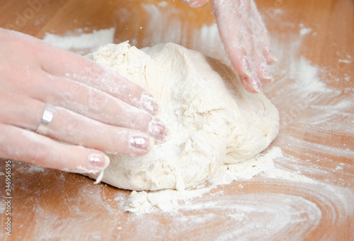 Female hands knead, knead the pizza dough. Dough, flour, cook, pizza. Girl rolls rolling pin dough