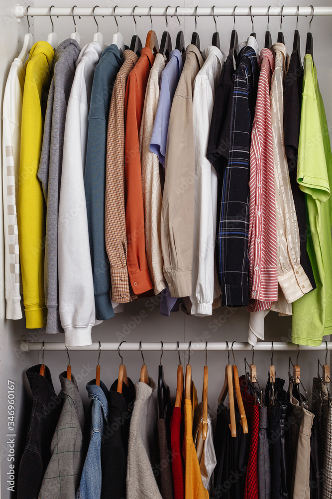 Front view of clothes hung on hangers in the dressing room on the white bar Front view of clothes hung on hangers in the dressing room on the white bar
