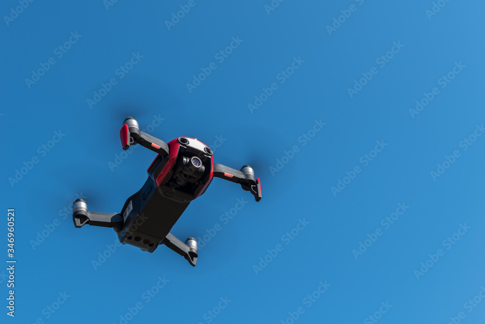 Small sized red drone with high resolution camera hovering in air for aerial photography. Small sized red drone with high resolution camera hovering in air for aerial photography.
