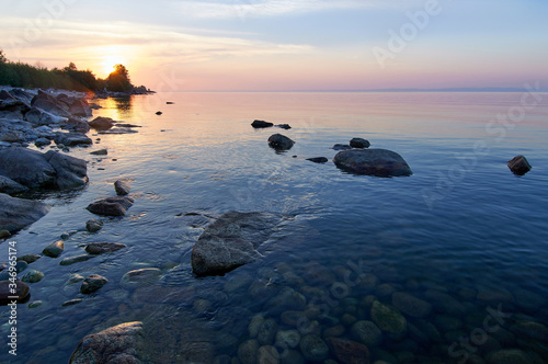 Lake Baikal in the summer at dawn. In the foreground is clear water and stones under water.