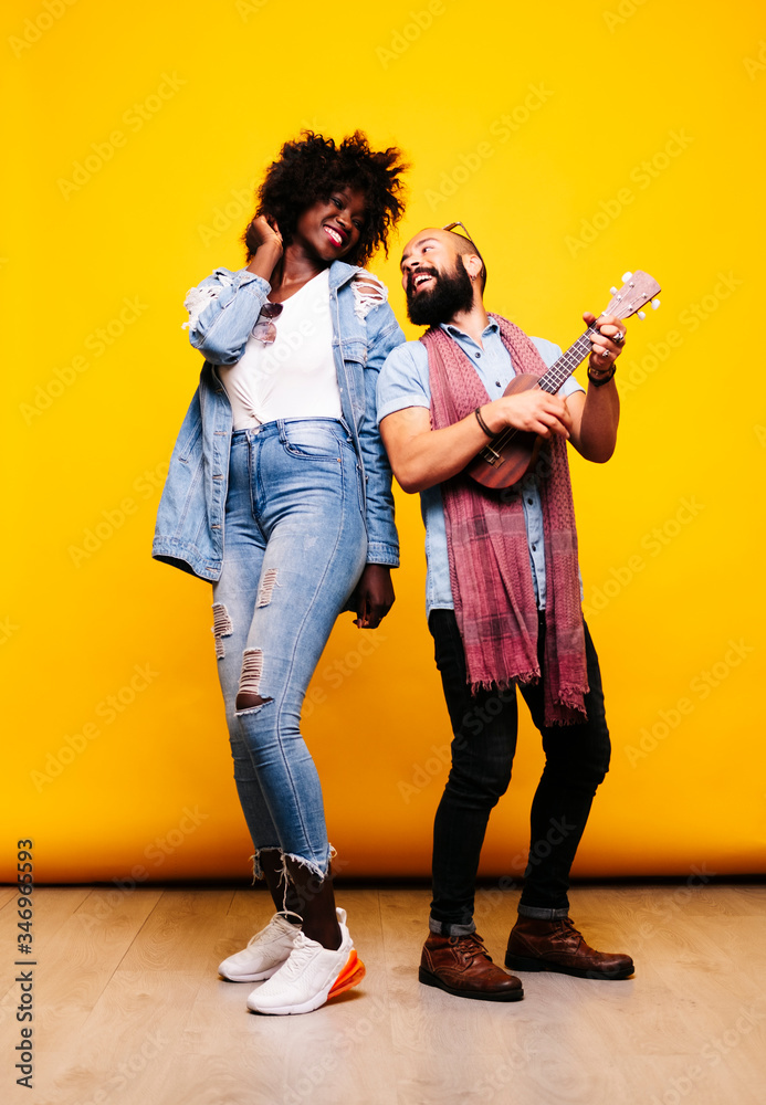 Happy young man with woman in studio playing ukulele