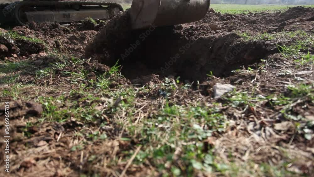 Close up of mechanical shovel filling a hole in a meadow with gravel. Concept: industrial earthmoving activity Close up of mechanical shovel filling a hole in a meadow with gravel. Concept: industrial earthmoving activity