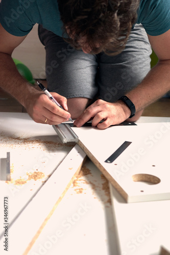 Man doing renovation work at home, drilling with a screwdriver. Group of repair tools on wooden white background.