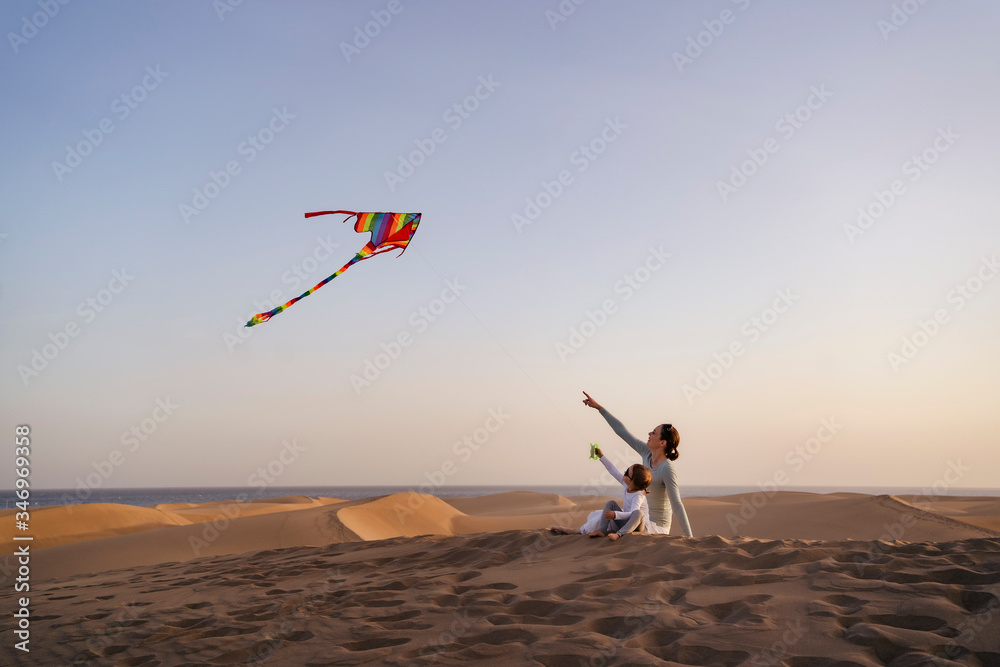 Mother and daughter flying kite in sand dunes, Gran Canaria, Spain