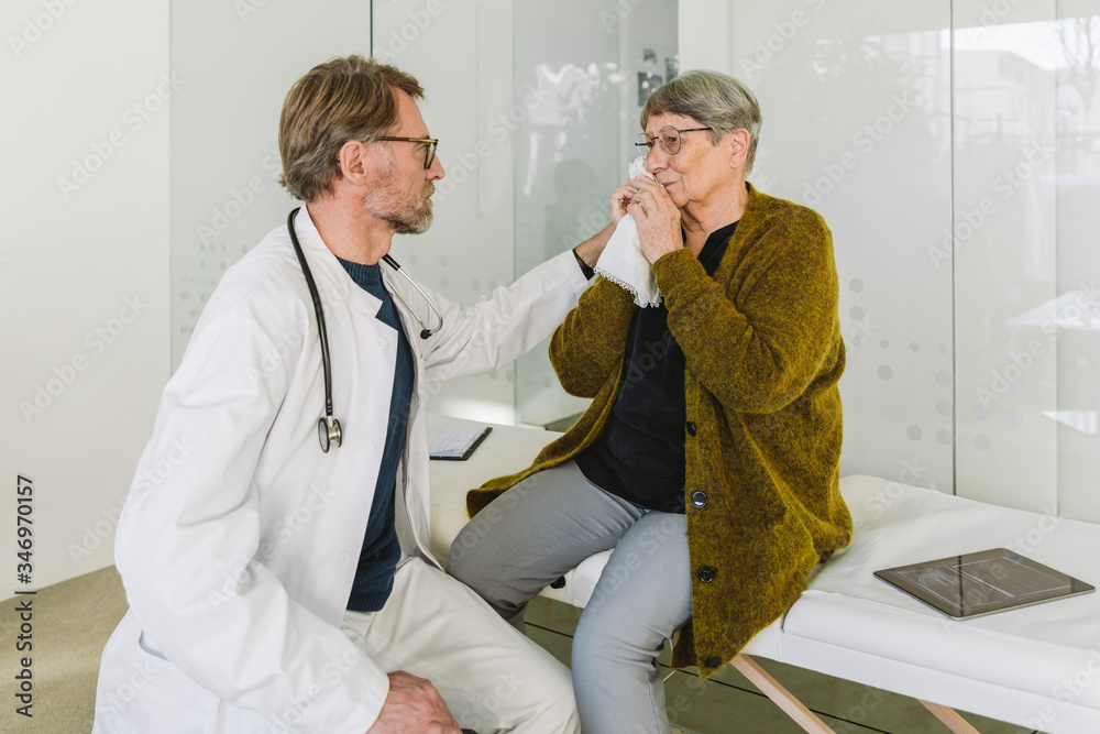 Doctor comforting sad senior patient in medical practice
