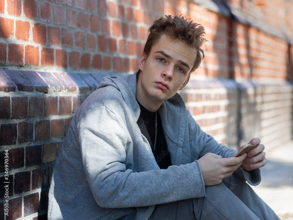 portrait of a confident, arrogant teenager with a phone on the street portrait of a confident, arrogant teenager with a phone on the street