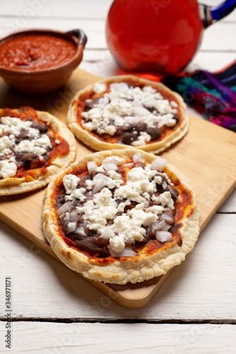 Mexican red sopes with cheese and beans on white background