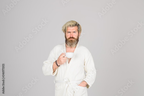 Serious man with cup of coffee in hand. Coffee. Morning. Tired man. Copy space for yours advertise. Bearded man holds mug with hot drink. Breakfast. photo