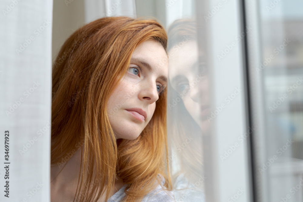 Portrait of serious young woman looking out of window