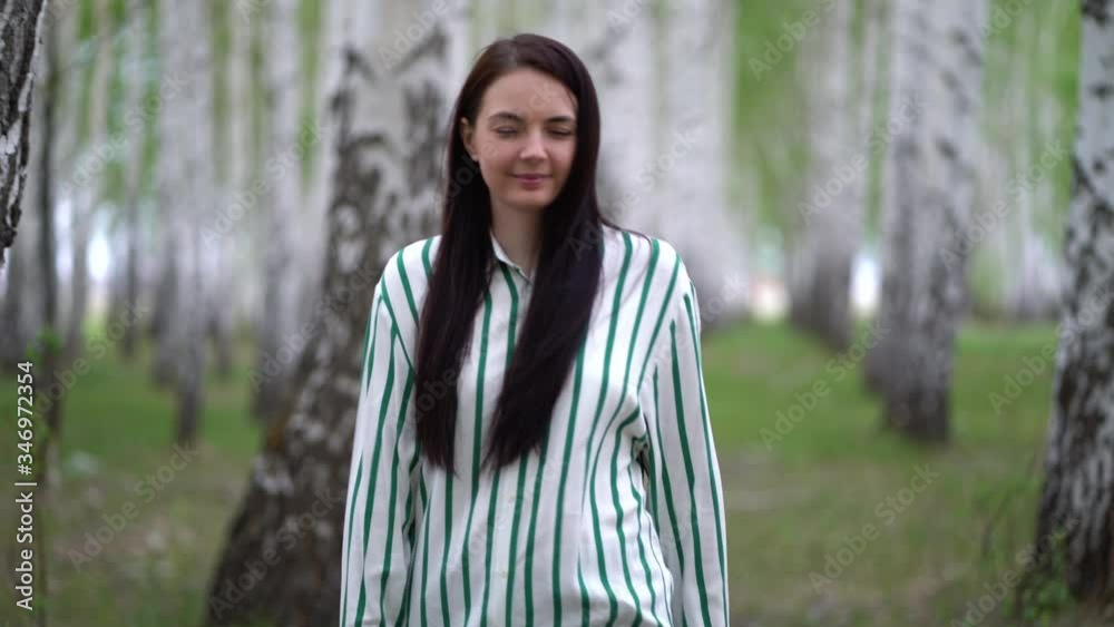 Girl walks in a birch grove on a spring day. Birch tree alley landscape.