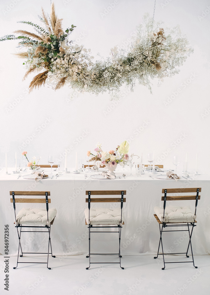 Obraz premium festive table with a floral bouquet, candles, chairs and a flower garland