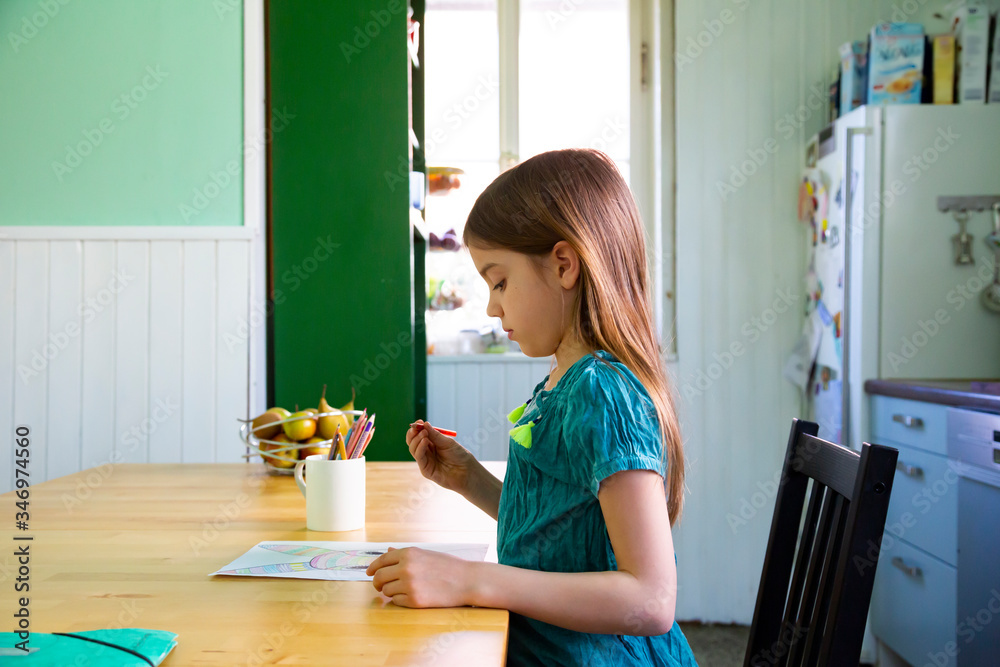 Little girl sitting at kitchen table, drawing an Easter bunny Little girl sitting at kitchen table, drawing an Easter bunny