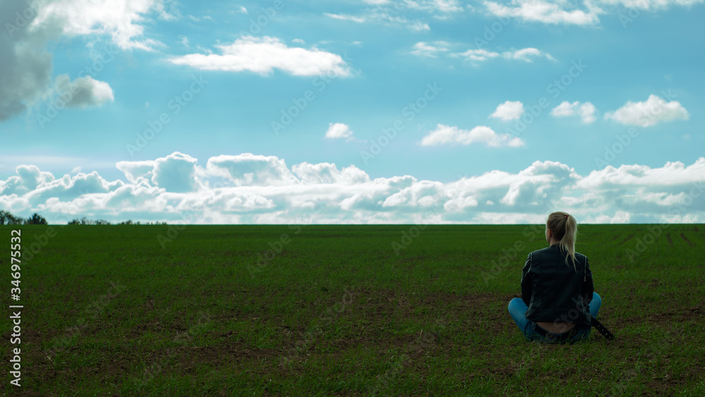 The girl sits alone in the field