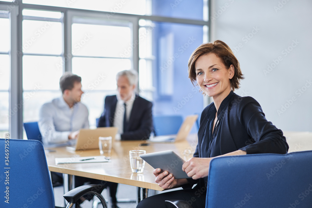 Portrait of smiling businesswoman with tablet during a meeting in office Portrait of smiling businesswoman with tablet during a meeting in office