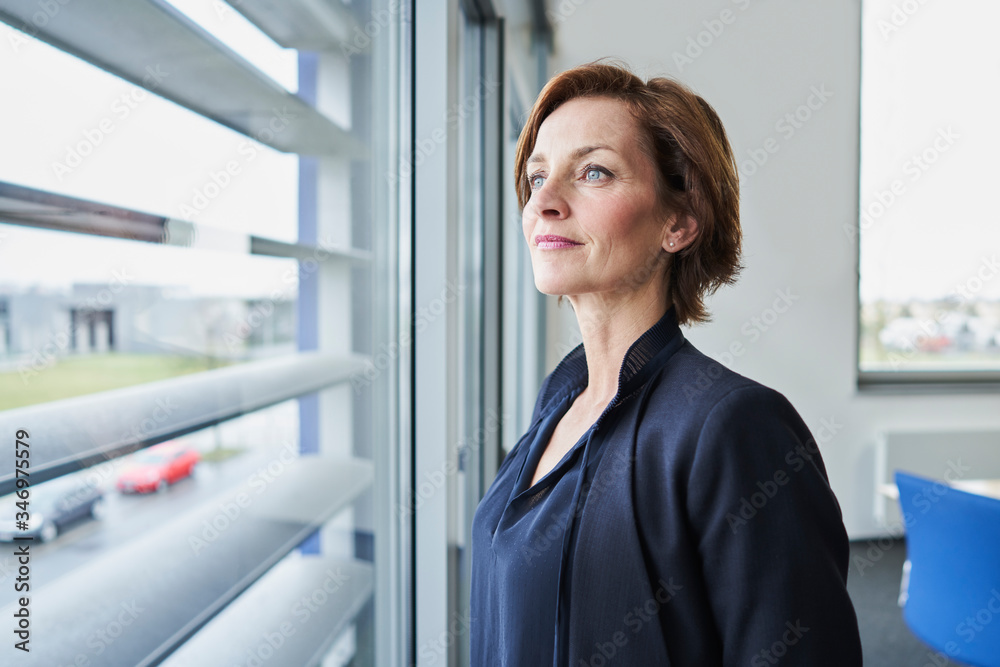 Portrait of confident businesswoman looking out of window Portrait of confident businesswoman looking out of window