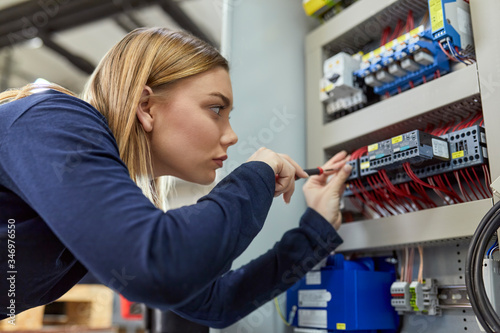 Female electrician working on circuitry in workshop photo